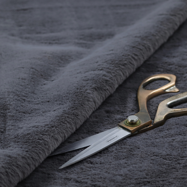 A luxurious faux fur fabric in a deep slate grey or charcoal blue shade. The material features a dense, plush, short-pile texture that creates a soft, uniform surface with a rich matte finish. The tightly packed fibres catch the light to reveal subtle, cool-toned depth and soft shadows, suggesting a velvety and sophisticated hand-feel.