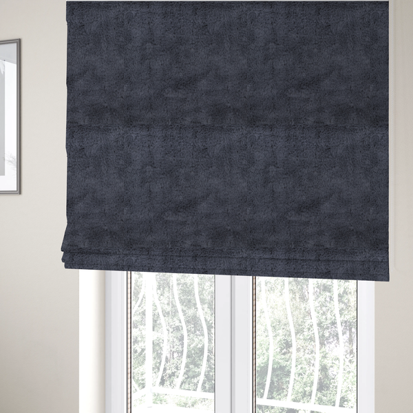 The fabric used to create these Roman blinds is a luxurious faux fur fabric in a deep slate grey or charcoal blue shade. The material features a dense, plush, short-pile texture that creates a soft, uniform surface with a rich matte finish. The tightly packed fibres catch the light to reveal subtle, cool-toned depth and soft shadows, suggesting a velvety and sophisticated hand-feel.