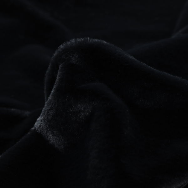 A luxurious faux fur fabric in a solid, true jet black. The material showcases an exceptionally dense, short-pile texture with a soft, uniform grain that creates a deep matte finish. Because of its high density, the fabric absorbs light significantly, resulting in a rich, velvety appearance with minimal sheen.