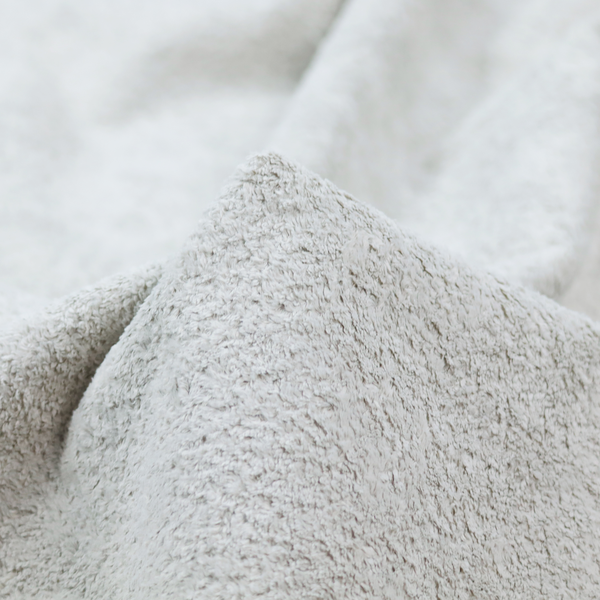 This fabric features a high-pile faux fur texture that offers a cool-toned, plush aesthetic with a rich tactile quality.