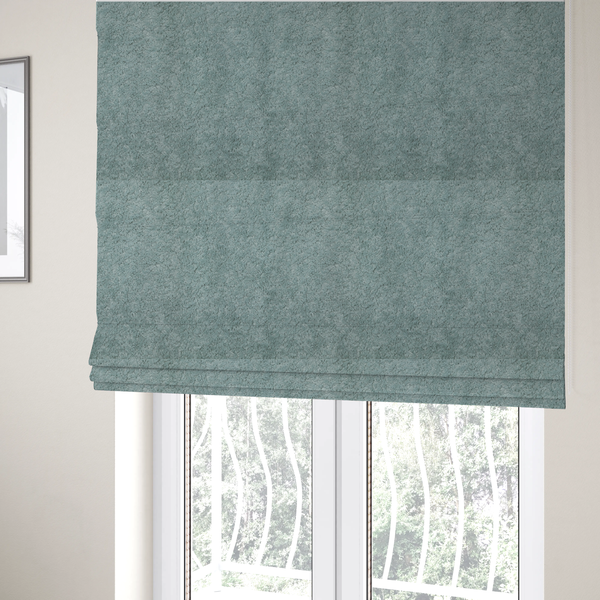 The fabric used to create these Roman blinds is a soft, textured fabric in a muted, calming shade of blue. The surface features a dense, uniform, and plush pile texture.