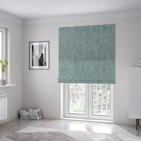 The fabric used to create these Roman blinds is a soft, textured fabric in a muted, calming shade of blue. The surface features a dense, uniform, and plush pile texture.