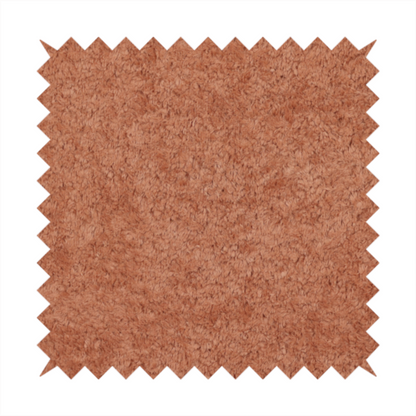 A soft, textured fabric in a warm, muted terracotta or rust shade. The surface features a dense, uniform, and plush pile, characteristic of thick fleece or absorbent terry cloth material.