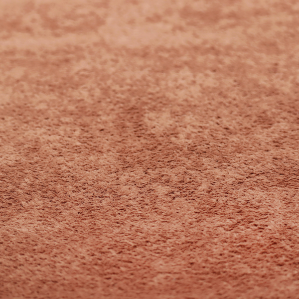 A soft, textured fabric in a warm, muted terracotta or rust shade. The surface features a dense, uniform, and plush pile, characteristic of thick fleece or absorbent terry cloth material.