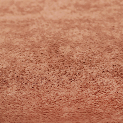 A soft, textured fabric in a warm, muted terracotta or rust shade. The surface features a dense, uniform, and plush pile, characteristic of thick fleece or absorbent terry cloth material.