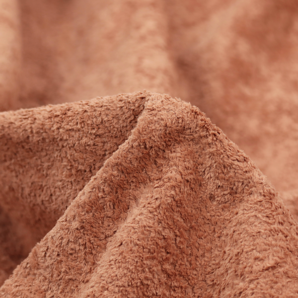 A soft, textured fabric in a warm, muted terracotta or rust shade. The surface features a dense, uniform, and plush pile, characteristic of thick fleece or absorbent terry cloth material.