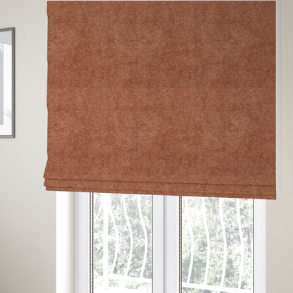The fabric used to create these Roman blinds is a soft, textured fabric in a warm, muted terracotta or rust shade. The surface features a dense, uniform, and plush pile, characteristic of thick fleece or absorbent terry cloth material.