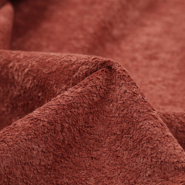 A soft, textured fabric in a deep, warm reddish-terracotta shade. The surface features a dense, uniform, and plush pile, characteristic of thick fleece or absorbent material.