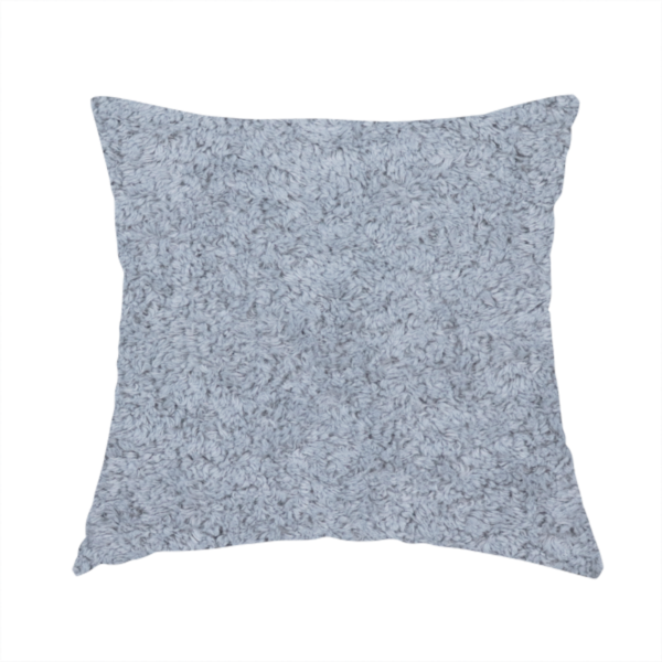 The fabric used to create this handmade cushion is a soft greyish-blue fabric with a dense, uniform, textured pile like thick fleece.