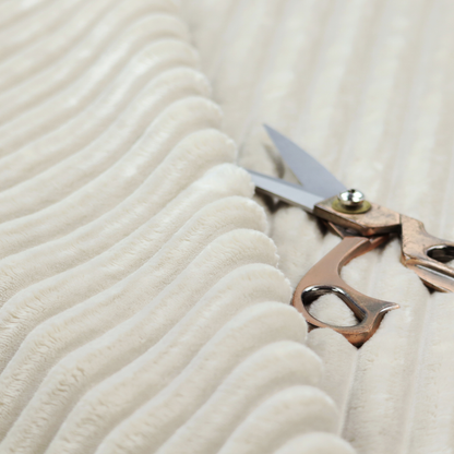 A detailed view of a light beige or cream-coloured textile featuring a repeating, vertical channel-tufted pattern. The material alternates between soft, high-pile plush bands and thin, compressed vertical lines.