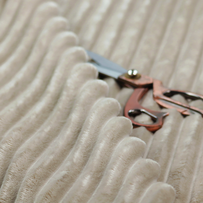 A warm, beige-toned textile featuring a repeating, vertical channel-tufted pattern. The fabric alternates between thick, high-pile plush bands and thin, compressed vertical channels.