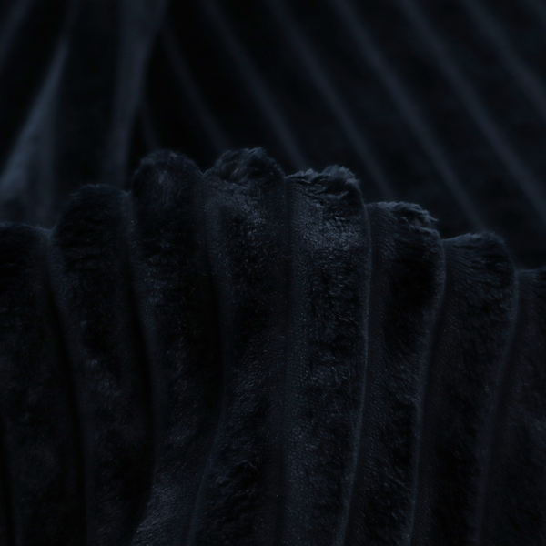 A deep black textile featuring a repeating, vertical channel-tufted pattern. The fabric alternates between thick, high-pile plush bands and thin, compressed vertical channels.