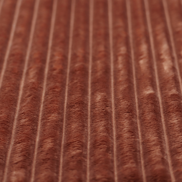 A orange rust, vertically ribbed, channel-tufted plush fabric with a soft, fuzzy texture.