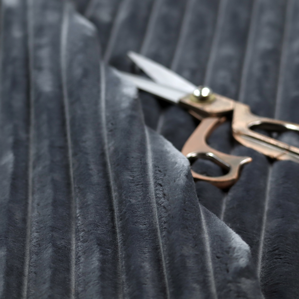 A charcoal grey, vertically ribbed, channel-tufted plush fabric.
