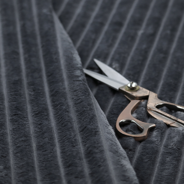 A charcoal grey, vertically ribbed, channel-tufted plush fabric.