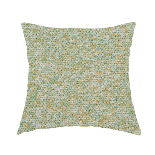 The fabric used to create this handmade cushion is a pale sage green, soft yellow, and white textured upholstery fabric.