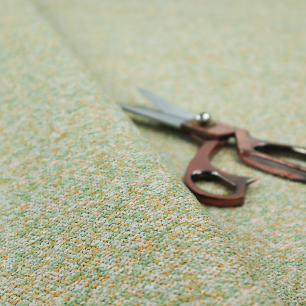 A pale sage green, soft yellow, and white textured upholstery fabric.