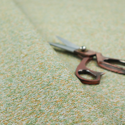 A pale sage green, soft yellow, and white textured upholstery fabric.