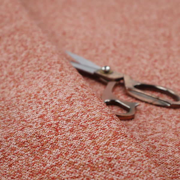 A soft coral and cream upholstery fabric featuring a detailed, textured, and nubby weave.