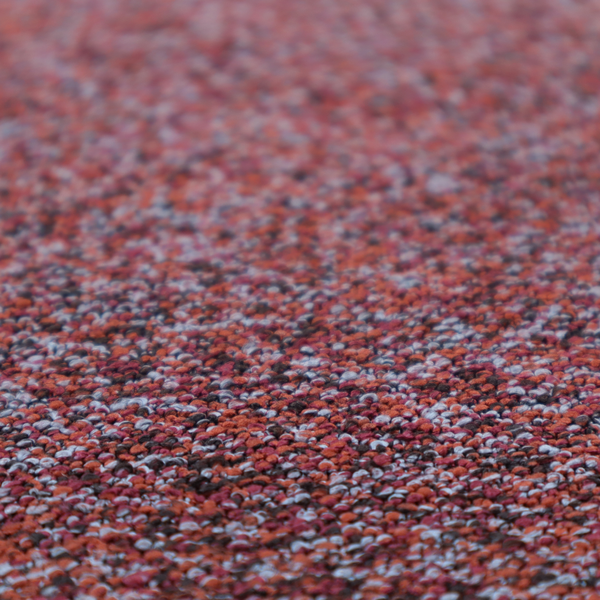 A warm, rustic red and deep terracotta upholstery fabric, showcasing a complex, nubby texture and rich colour variation.