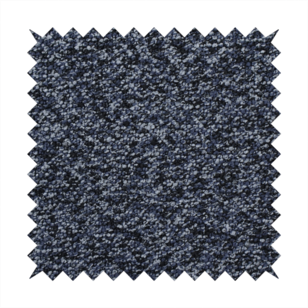 A textured fabric surface. The material features a dense, nubby appearance with a speckled, multi-tonal colour palette of dark navy blue, charcoal, and light grey fibres, characteristic of heavy-duty carpeting or upholstery.