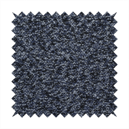 A textured fabric surface. The material features a dense, nubby appearance with a speckled, multi-tonal colour palette of dark navy blue, charcoal, and light grey fibres, characteristic of heavy-duty carpeting or upholstery.