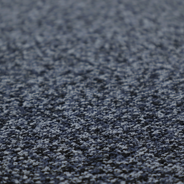 A textured fabric surface. The material features a dense, nubby appearance with a speckled, multi-tonal colour palette of dark navy blue, charcoal, and light grey fibres, characteristic of heavy-duty carpeting or upholstery.