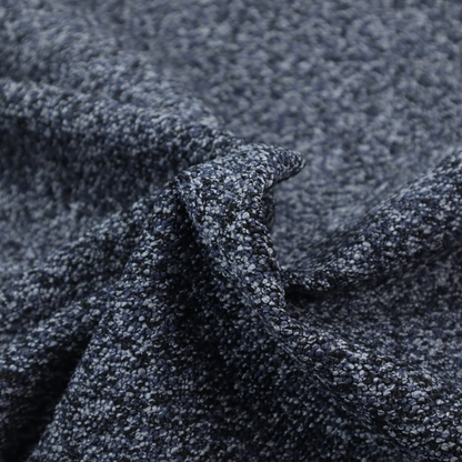 A textured fabric surface. The material features a dense, nubby appearance with a speckled, multi-tonal colour palette of dark navy blue, charcoal, and light grey fibres, characteristic of heavy-duty carpeting or upholstery.
