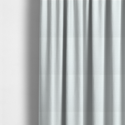 The fabric used to create these made-to-measure curtains is a white, textured fabric with a dense, rhythmic pattern. The material features a honeycomb or waffle-weave structure, where small, uniform raised circles create a grid-like tactile surface. The colour is a bright, cool-toned white, and the subtle shadows within the weave give the fabric a soft, multidimensional appearance.