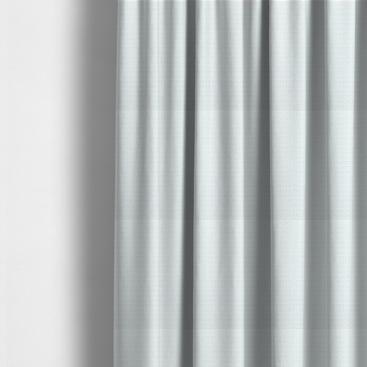 The fabric used to create these made-to-measure curtains is a white, textured fabric with a dense, rhythmic pattern. The material features a honeycomb or waffle-weave structure, where small, uniform raised circles create a grid-like tactile surface. The colour is a bright, cool-toned white, and the subtle shadows within the weave give the fabric a soft, multidimensional appearance.