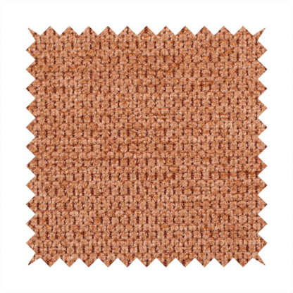 A textured, deep terracotta or burnt orange fabric. This material features a dense, uniform weave with a tactile, honeycombed surface. The colour is a rich, saturated earth tone, created by tightly interlacing copper-coloured threads that catch the light, giving the fabric a subtle, warm glow and a complex, pebbled depth.