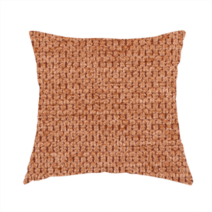The fabric used to create this handmade cushion is a textured, deep terracotta or burnt orange fabric. This material features a dense, uniform weave with a tactile, honeycombed surface. The colour is a rich, saturated earth tone, created by tightly interlacing copper-coloured threads that catch the light, giving the fabric a subtle, warm glow and a complex, pebbled depth.