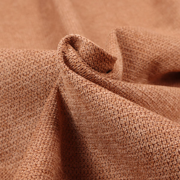 A textured, deep terracotta or burnt orange fabric. This material features a dense, uniform weave with a tactile, honeycombed surface. The colour is a rich, saturated earth tone, created by tightly interlacing copper-coloured threads that catch the light, giving the fabric a subtle, warm glow and a complex, pebbled depth.