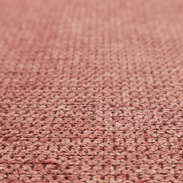 A textured fabric in a muted rose or dusty clay tone. The material features a dense, rhythmic weave with a tactile, pebbled surface. The colour is a sophisticated, warm mauve, created by interlacing deep pinkish-brown threads with lighter rose fibres, giving it a weathered, multi-dimensional look.