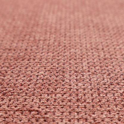 A textured fabric in a muted rose or dusty clay tone. The material features a dense, rhythmic weave with a tactile, pebbled surface. The colour is a sophisticated, warm mauve, created by interlacing deep pinkish-brown threads with lighter rose fibres, giving it a weathered, multi-dimensional look.