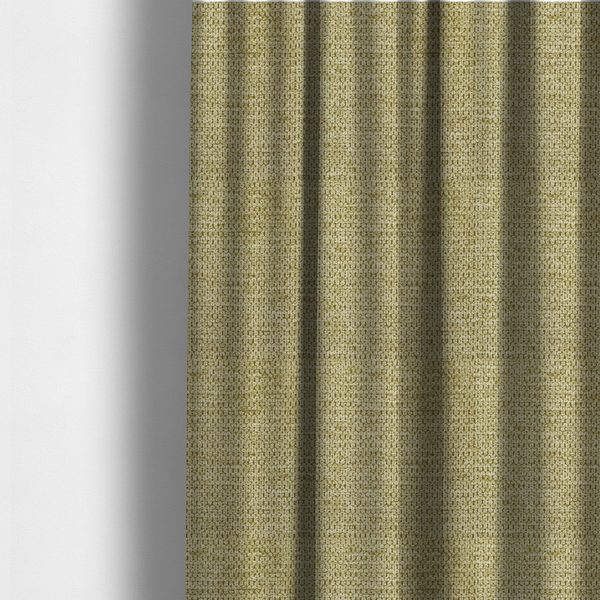 The fabric used to create these made-to-measure curtains is a textured fabric in a warm olive or golden-khaki tone. The material features a tight, rhythmic weave with a prominent tactile surface. The colour is a rich, earthy sage, achieved by interlacing olive-green threads with lighter tan and straw-coloured fibres, creating a weathered, organic look that shifts beautifully in the light.