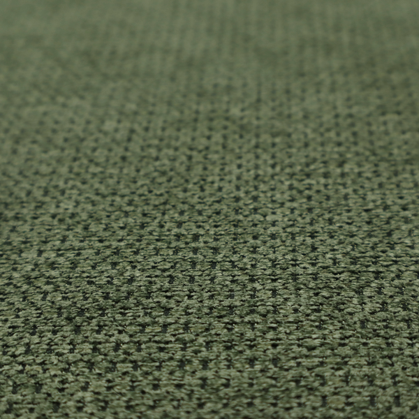A textured fabric in a deep forest or moss green tone. The material features a dense, rhythmic weave with a prominent tactile surface. The colour is a rich, moody evergreen, achieved by interlacing dark green threads with subtle black or charcoal base fibres, creating a sophisticated, shadowed depth throughout the honeycomb-like pattern.