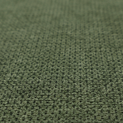 A textured fabric in a deep forest or moss green tone. The material features a dense, rhythmic weave with a prominent tactile surface. The colour is a rich, moody evergreen, achieved by interlacing dark green threads with subtle black or charcoal base fibres, creating a sophisticated, shadowed depth throughout the honeycomb-like pattern.
