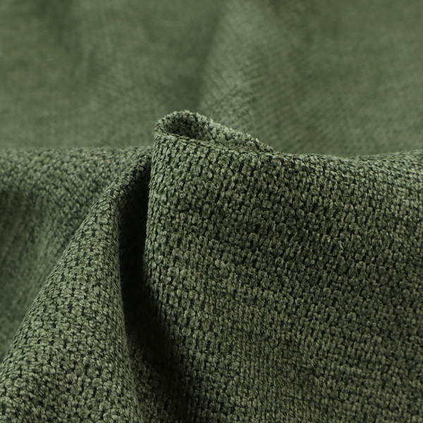 A textured fabric in a deep forest or moss green tone. The material features a dense, rhythmic weave with a prominent tactile surface. The colour is a rich, moody evergreen, achieved by interlacing dark green threads with subtle black or charcoal base fibres, creating a sophisticated, shadowed depth throughout the honeycomb-like pattern.