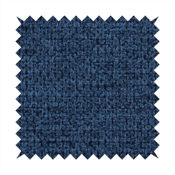 A textured fabric in a deep navy or midnight blue tone. The material features a dense, rhythmic weave with a prominent tactile surface. The colour is a rich, saturated indigo, achieved by interlacing vibrant blue threads with darker charcoal base fibres, creating a sophisticated, shadowed depth throughout the honeycomb-like pattern.
