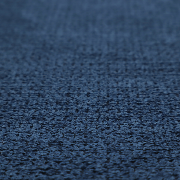 A textured fabric in a deep navy or midnight blue tone. The material features a dense, rhythmic weave with a prominent tactile surface. The colour is a rich, saturated indigo, achieved by interlacing vibrant blue threads with darker charcoal base fibres, creating a sophisticated, shadowed depth throughout the honeycomb-like pattern.