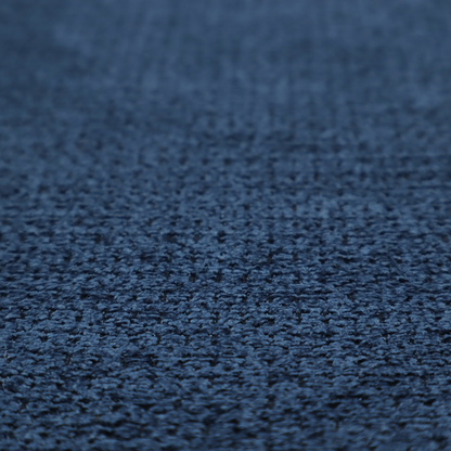 A textured fabric in a deep navy or midnight blue tone. The material features a dense, rhythmic weave with a prominent tactile surface. The colour is a rich, saturated indigo, achieved by interlacing vibrant blue threads with darker charcoal base fibres, creating a sophisticated, shadowed depth throughout the honeycomb-like pattern.