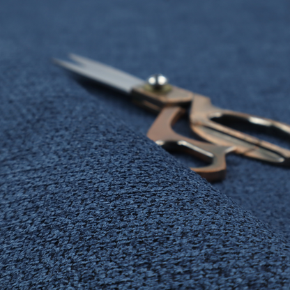 A textured fabric in a deep navy or midnight blue tone. The material features a dense, rhythmic weave with a prominent tactile surface. The colour is a rich, saturated indigo, achieved by interlacing vibrant blue threads with darker charcoal base fibres, creating a sophisticated, shadowed depth throughout the honeycomb-like pattern.