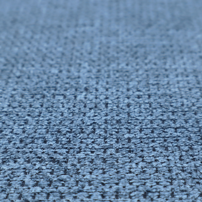 A textured fabric in a serene slate or denim blue tone. This material features a dense, rhythmic weave with a tactile, honeycomb-like surface. The colour is a cool, mid-toned blue, achieved by interlacing cornflower blue threads with darker charcoal base fibres, resulting in a weathered, multidimensional look that feels both calm and sturdy.