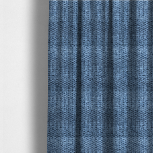 The fabric used to create these made-to-measure curtains is a textured fabric in a serene slate or denim blue tone. This material features a dense, rhythmic weave with a tactile, honeycomb-like surface. The colour is a cool, mid-toned blue, achieved by interlacing cornflower blue threads with darker charcoal base fibres, resulting in a weathered, multidimensional look that feels both calm and sturdy.