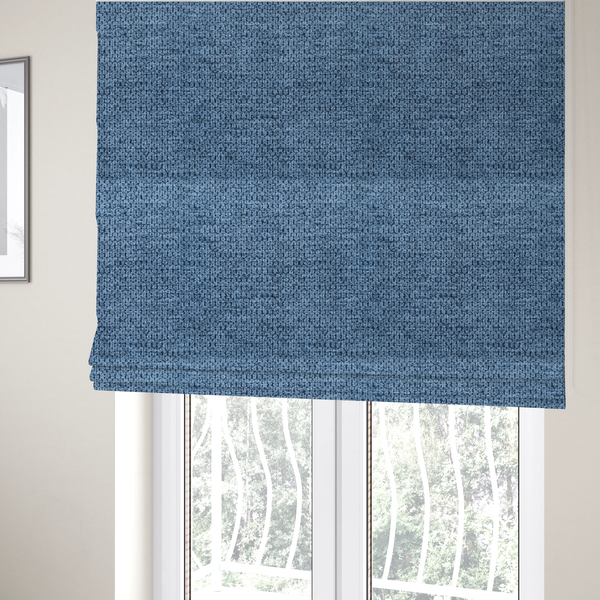 The fabric used to create these Roman blinds is a textured fabric in a serene slate or denim blue tone. This material features a dense, rhythmic weave with a tactile, honeycomb-like surface. The colour is a cool, mid-toned blue, achieved by interlacing cornflower blue threads with darker charcoal base fibres, resulting in a weathered, multidimensional look that feels both calm and sturdy.