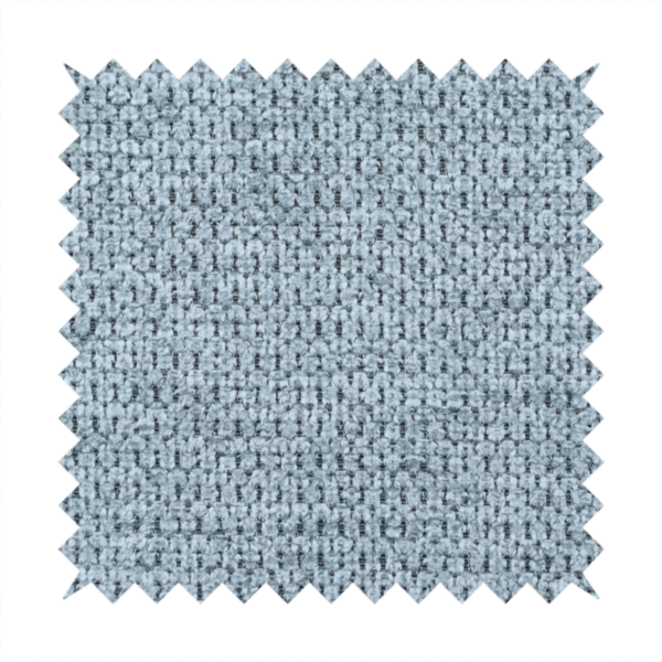 A textured fabric in a light steel or airy powder blue. This material features a dense, rhythmic weave with a tactile, honeycomb-like surface. The colour is a cool, soft frost blue, achieved by interlacing pale blue threads with darker grey base fibres, resulting in a weathered, multidimensional look that feels light yet substantial.