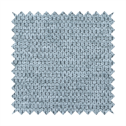 A textured fabric in a light steel or airy powder blue. This material features a dense, rhythmic weave with a tactile, honeycomb-like surface. The colour is a cool, soft frost blue, achieved by interlacing pale blue threads with darker grey base fibres, resulting in a weathered, multidimensional look that feels light yet substantial.