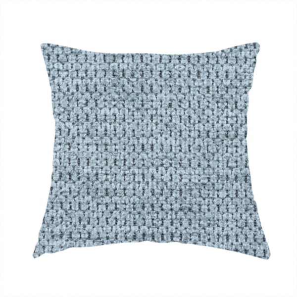 The fabric used to create this handmade cushion is a textured fabric in a light steel or airy powder blue. This material features a dense, rhythmic weave with a tactile, honeycomb-like surface. The colour is a cool, soft frost blue, achieved by interlacing pale blue threads with darker grey base fibres, resulting in a weathered, multidimensional look that feels light yet substantial.