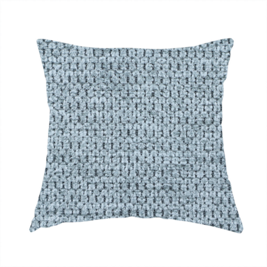 The fabric used to create this handmade cushion is a textured fabric in a light steel or airy powder blue. This material features a dense, rhythmic weave with a tactile, honeycomb-like surface. The colour is a cool, soft frost blue, achieved by interlacing pale blue threads with darker grey base fibres, resulting in a weathered, multidimensional look that feels light yet substantial.